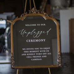 a welcome sign is hanging from a metal easel in front of a mirror that reads, welcome to our wedding ceremony