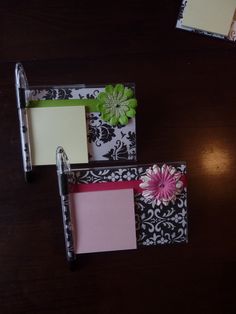 three notepads and a pen on a wooden table with black and white damask