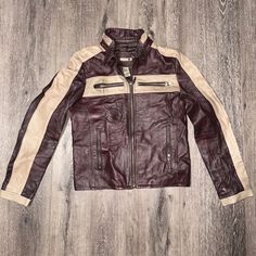 a brown and white leather jacket sitting on top of a wooden floor next to a wall