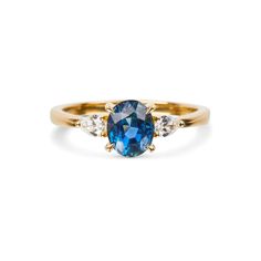 a blue and white diamond ring with three diamonds on the side, set in yellow gold