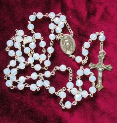 "This opalite rosary is made with 6mm faceted, round, semitransparent white manmade gemstones. This glass/mineral combination gives the beads a milky appearance, similar to opal. Silver plated chains separate the \"Our Father\" beads from the decades.  This rosary measures about 30 inches around and has a 5 inch cross drop. I hand turned the silver plated wires. This rosary will be slipped into a velvet bag and shipped in a bubble mailer." Catholic Rosary, Our Father, Rosary Catholic, Bubble Mailer, Velvet Bag, Semi Transparent, Prayer Beads, Rosary, Bead Charms