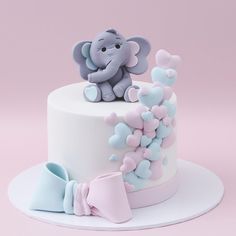 there is a cake decorated with an elephant and hearts on it, as well as a bow