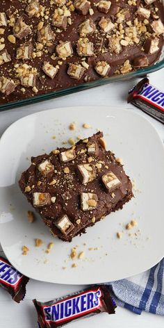 a white plate topped with a piece of cake next to a pan filled with chocolate