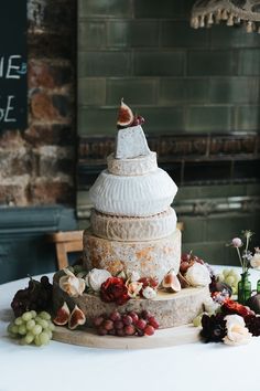 a table topped with a cake covered in cheese and grapes next to other food items