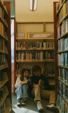 two people sitting on the floor in front of bookshelves