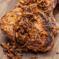 two pieces of meat sitting on top of a wooden cutting board