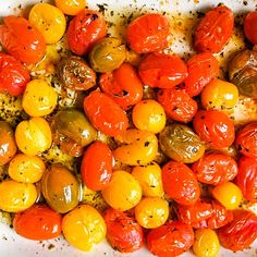 tomatoes and other vegetables are mixed together in a white dish with seasoning sprinkled on top