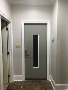 an empty room with a gray door and brick floor