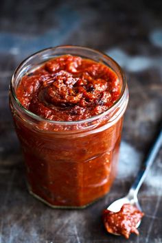 a jar filled with sauce next to a spoon