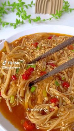 a bowl filled with noodles and chopsticks on top of a table