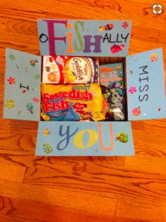 an open box filled with candy on top of a wooden floor next to a sign that says fish ally