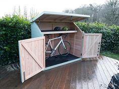 a bicycle is parked in the back of a storage shed on a wooden deck outside