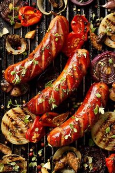 grilled sausages, onions and peppers on a grill with herbs sprinkled on them