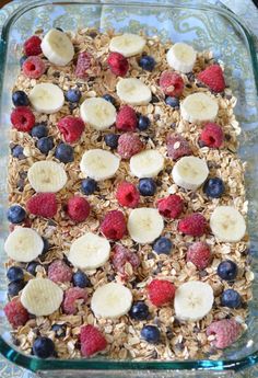 a glass dish filled with granola, raspberries and bananas