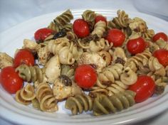 a white plate topped with pasta and cherry tomatoes