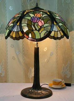 a lamp that is sitting on top of a table next to a cup and saucer