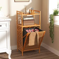 a wooden shelf with baskets and towels on it next to a potted houseplant