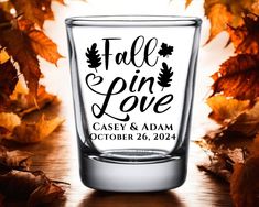 a shot glass with the words fall in love printed on it and leaves around it