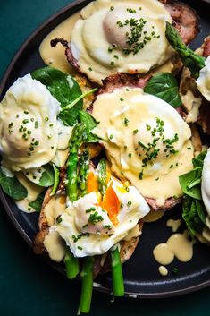 an egg benedict with asparagus and hollandaise sauce on a black plate