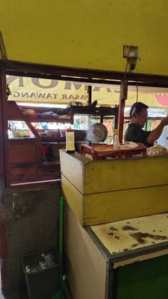 a man sitting at a counter in a food cart with lots of junk on it