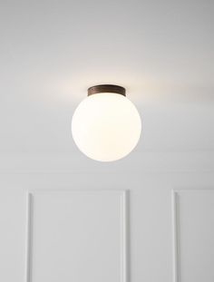 a white room with a round light fixture on the ceiling and two doors in the background