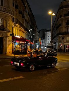 an old car is parked on the side of the road in front of some buildings