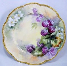 a plate with flowers painted on the side and gold trimming around the edge,