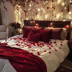 a bed with red and white pillows on top of it next to a wall covered in lights