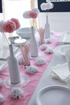 the table is set with pink and white flowers in vases, plates and napkins