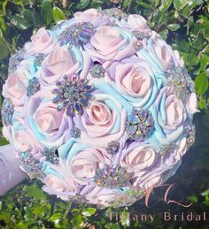 a bridal bouquet made up of pink and blue roses with crystals on the petals