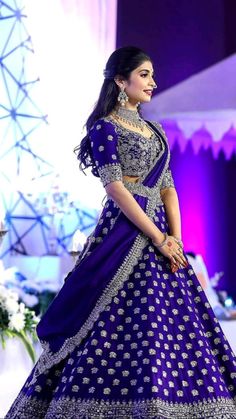 a woman in a blue and white lehenga is standing on the runway with her hands behind her back