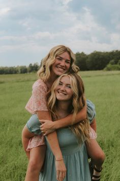 two young women hugging each other in a field