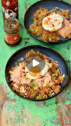 two black plates filled with food on top of a green table next to a jar of ketchup