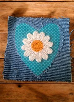 a piece of fabric with a white flower on it sitting on top of a wooden table