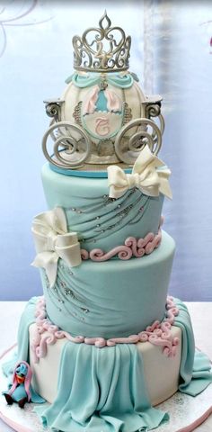 a three tiered cake with a tiara on top and ribbons around the edges