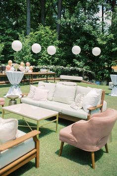 an outdoor setting with couches, chairs and tables in the grass at a wedding