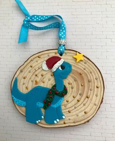 a christmas ornament with a blue dinosaur wearing a santa hat