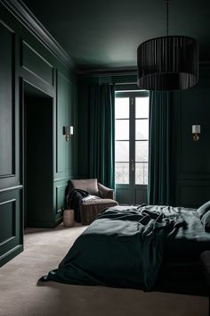 a bedroom with dark green walls and carpeted flooring is lit by a chandelier