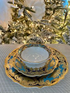 two blue and gold plates sitting on top of a table next to a christmas tree