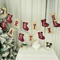 a christmas tree with stockings hanging from it's sides next to a white table