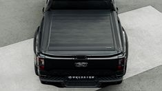 the back end of a black truck parked on top of a cement flooring area