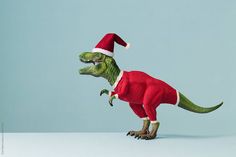 a toy dinosaur wearing a santa hat and standing on it's hind legs with its mouth open