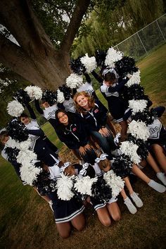 a group of cheerleaders posing in front of a tree