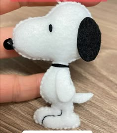 a hand holding a small white and black stuffed dog on top of a wooden table