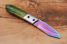 a green and purple knife on top of a wooden table