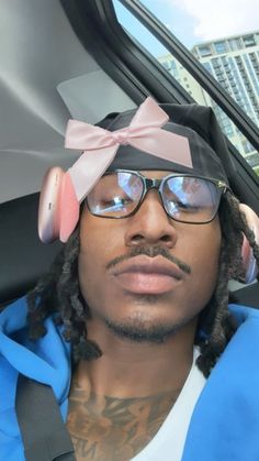 a man with glasses and a bow on his head sitting in the back seat of a car