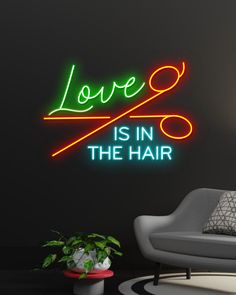 a neon sign that says love is in the hair on a wall next to a chair