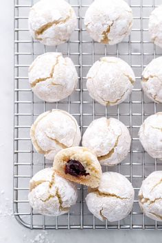 powdered sugar filled pastries on a cooling rack with jam in the middle, ready to be eaten