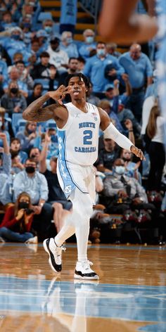 a basketball player is running on the court with his hand in the air while fans look on