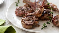 some meat is sitting on a white plate and garnished with parsleys